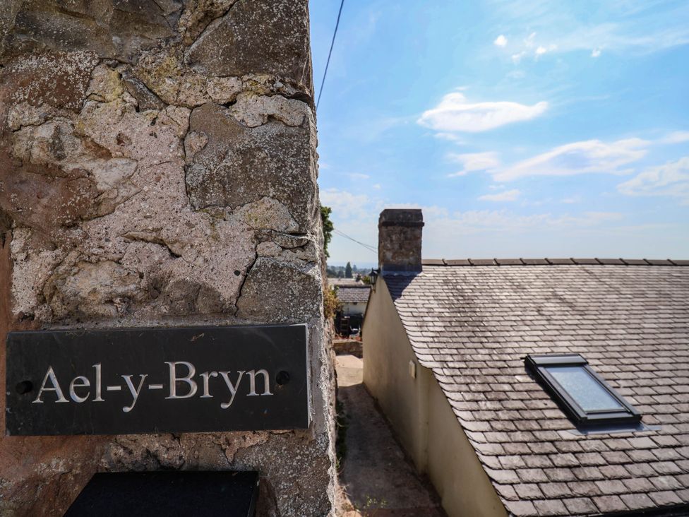 A sign on a wall in front of a roof and blue sky at Ael-y-Bryn in Dyserth