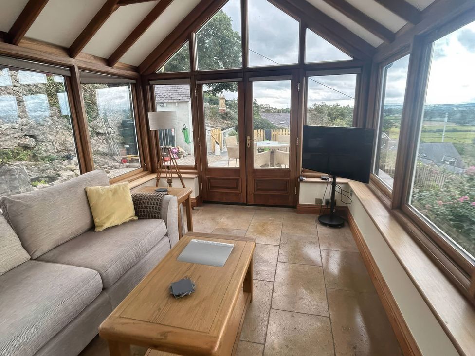 A conservatory with a sofa and television at Ael Y Bryn Dyserth