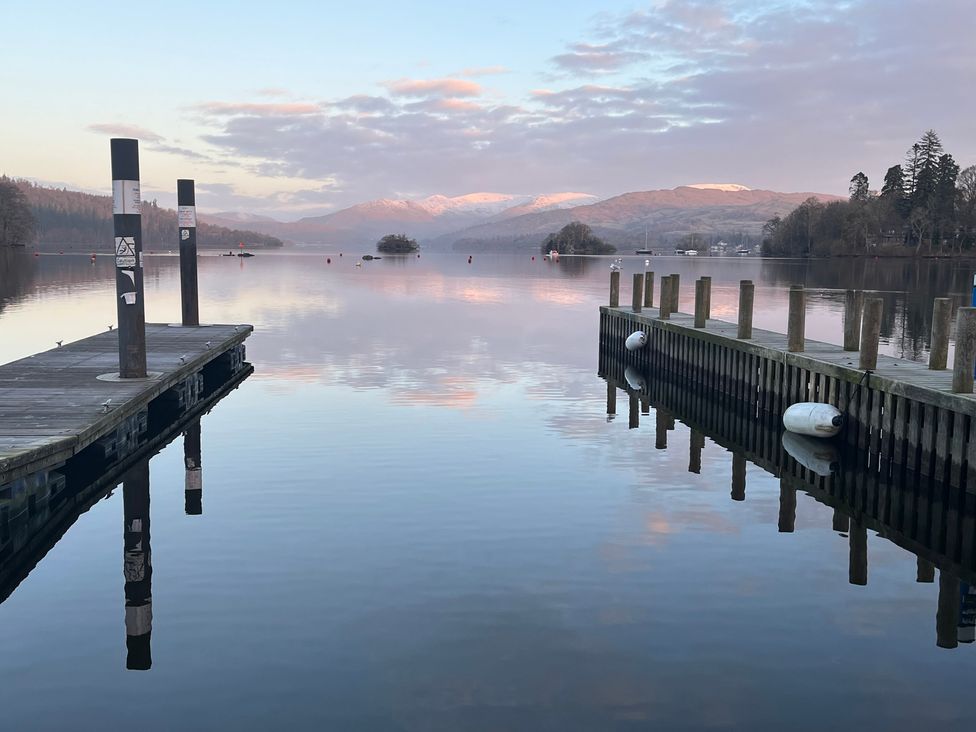 A dock over water with mountains in the background at Two West End in Bowness-On-Windermere
