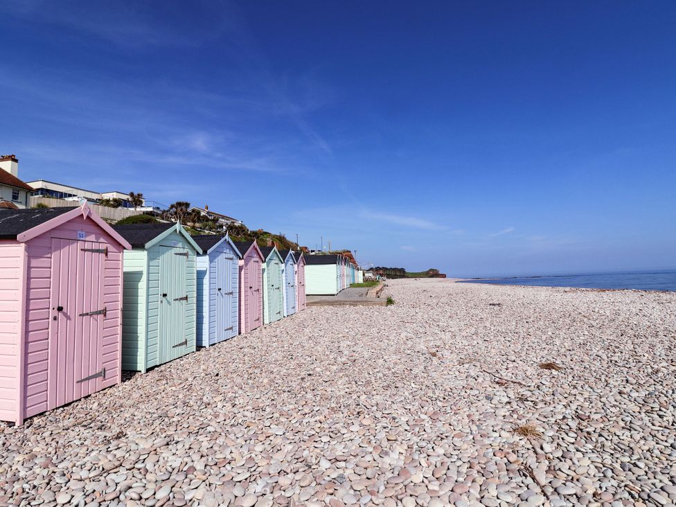 A row of beach huts along a pebbled beach at Badger's Den Budleigh Salterton