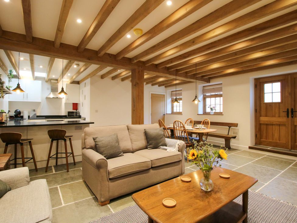 A living room with a sofa, coffee table and kitchen area at The Hideaway in Bishop's Castle