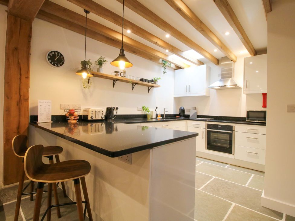A kitchen with bar stools and appliances at The Hideaway in Bishop's Castle