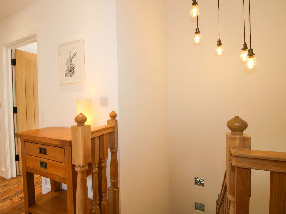 A hallway with a table and light fixtures at The Hideaway in Bishop's Castle