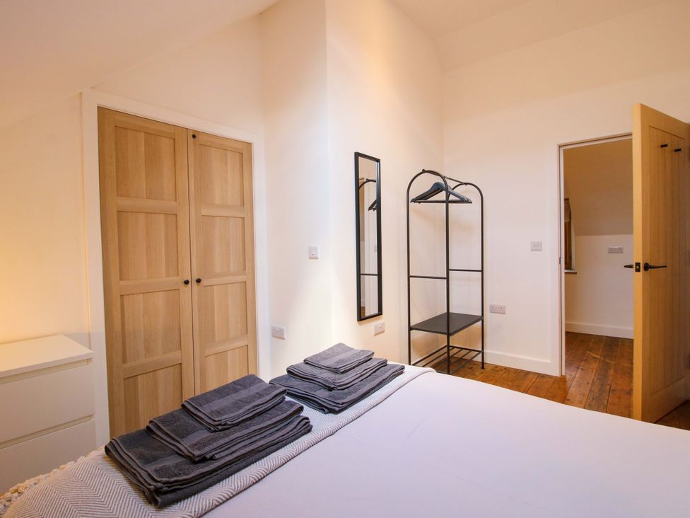 A bedroom with a bed, towels, mirrors and wardrobe at The Hideaway in Bishop's Castle