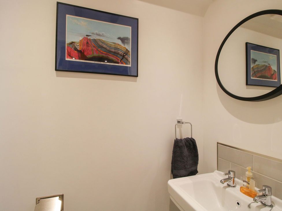 A bathroom with a washbasin, towel, and wall art at The Hideaway in Bishop's Castle