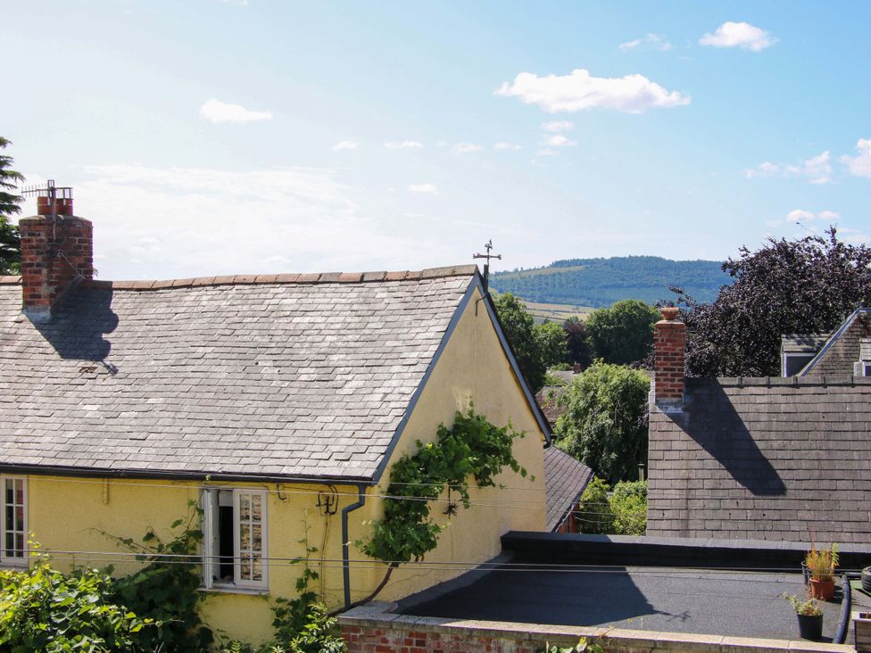 A view of rooftops and trees with hills in the background at The Hideaway in Bishop's Castle