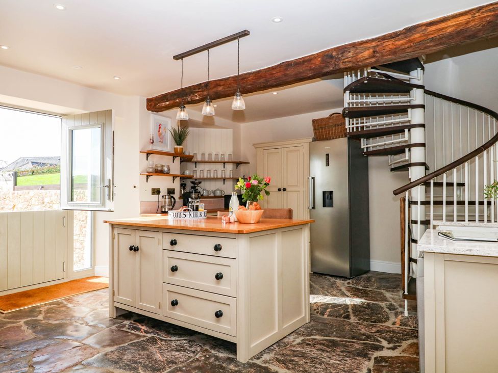 A kitchen featuring a kitchen island and spiral staircase at Higher Weekaborough Farm in Coombe Fishacre near Ipplepen