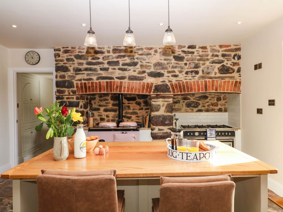 A kitchen with wooden table and clock at Higher Weekaborough Farm near Coombe Fishacre