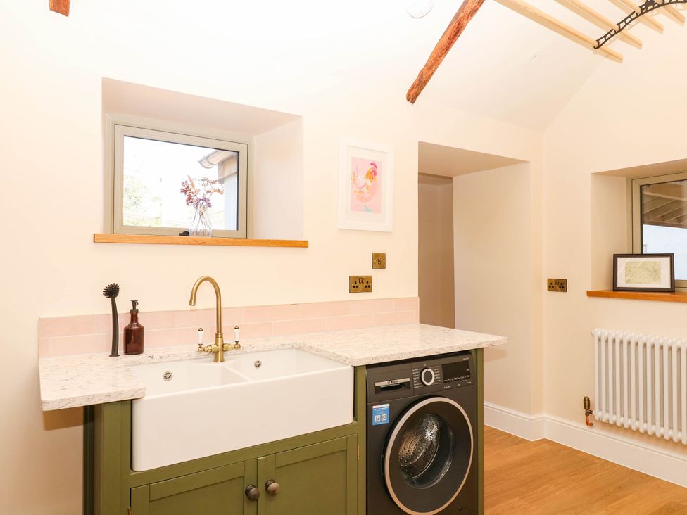 A utility room with a washing machine and sink at Higher Weekaborough Farm in Coombe Fishacre near Ipplepen