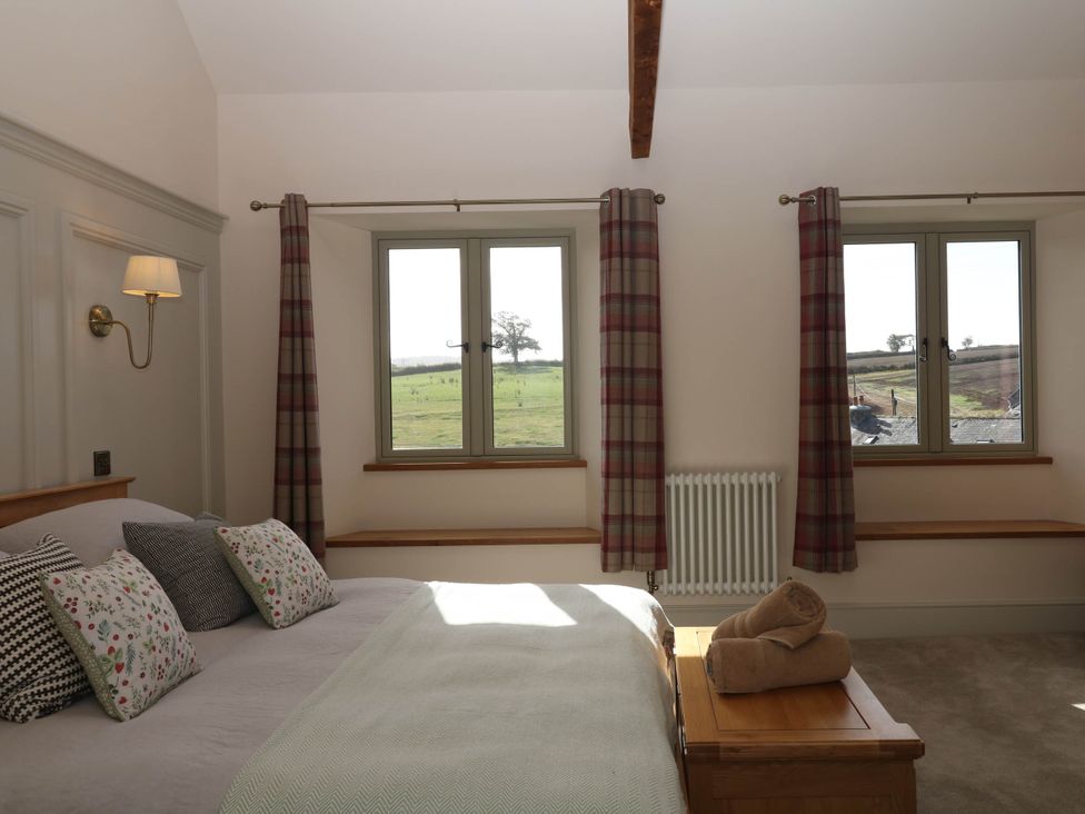 A bedroom with a bed and windows at Higher Weekaborough Farm near Ipplepen