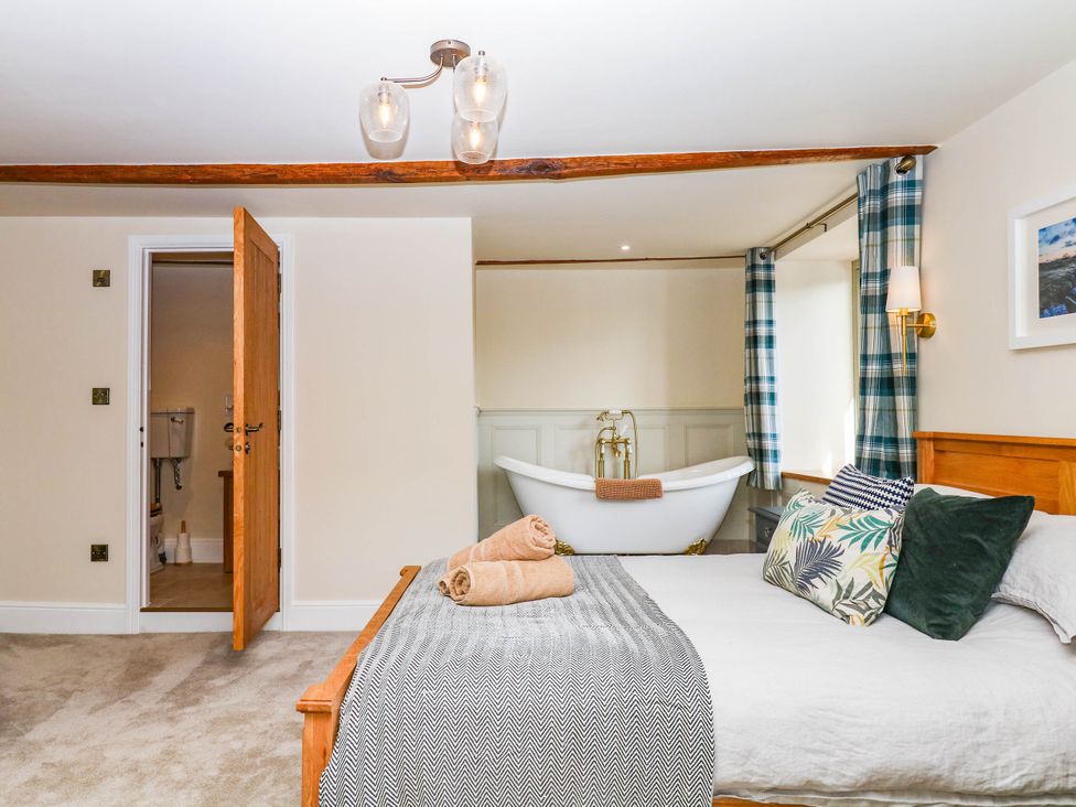A bedroom with a bed and a bathtub visible at Higher Weekaborough Farm in Coombe Fishacre near Ipplepen