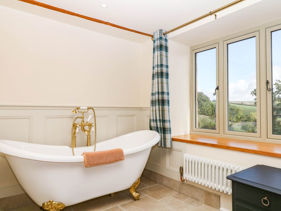 A bathroom with a bathtub and window at Higher Weekaborough Farm near Ipplepen