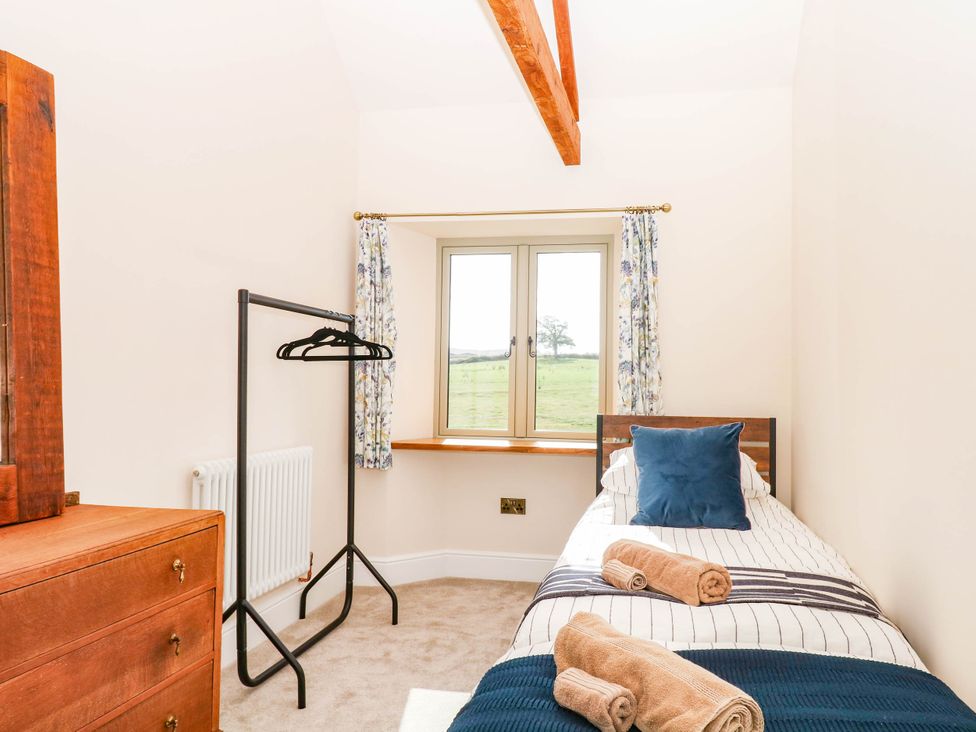 A bedroom with a bed and clothes rack at Higher Weekaborough Farm in Coombe Fishacre near Ipplepen