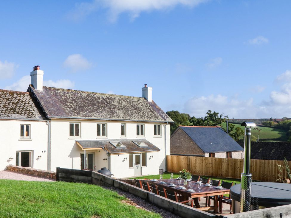 A house with an outdoor table and chairs at Higher Weekaborough Farm near Ipplepen