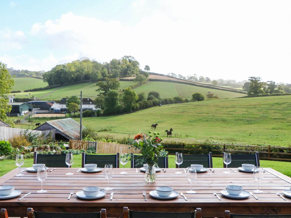 An outdoor dining area with a table set for meals at Higher Weekaborough Farm near Coombe Fishacre Ipplepen