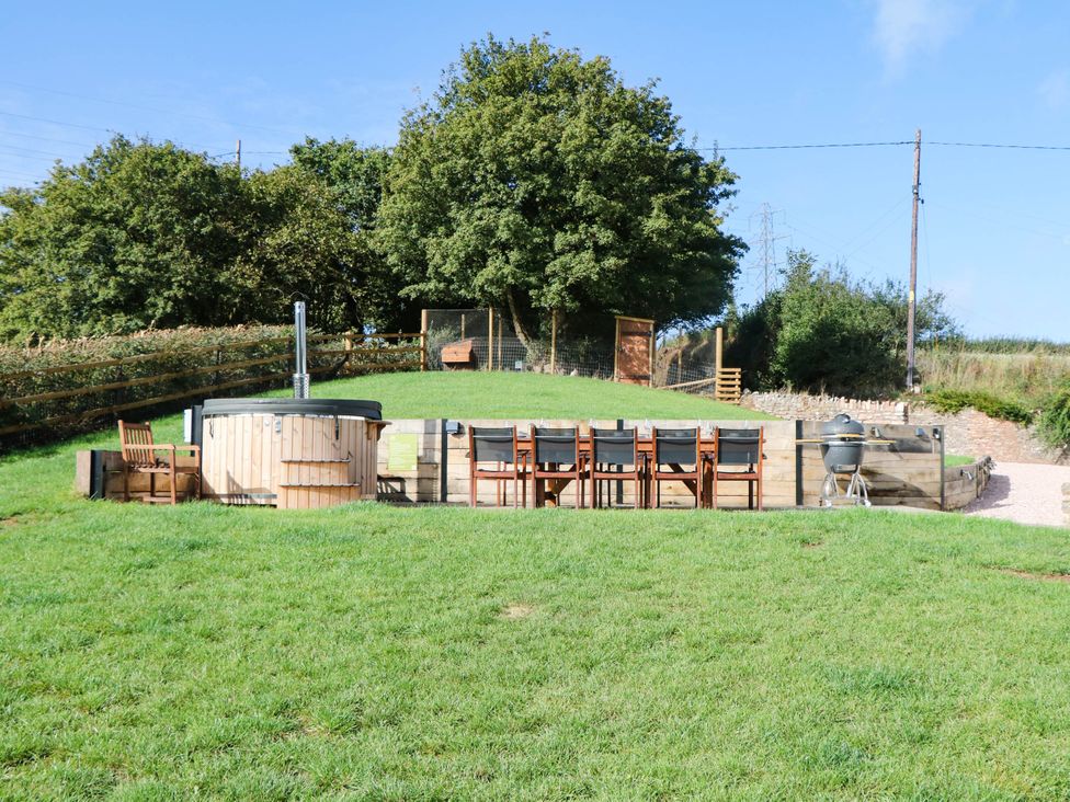 A garden with a hot tub and dining area at Higher Weekaborough Farm near Coombe Fishacre near Ipplepen