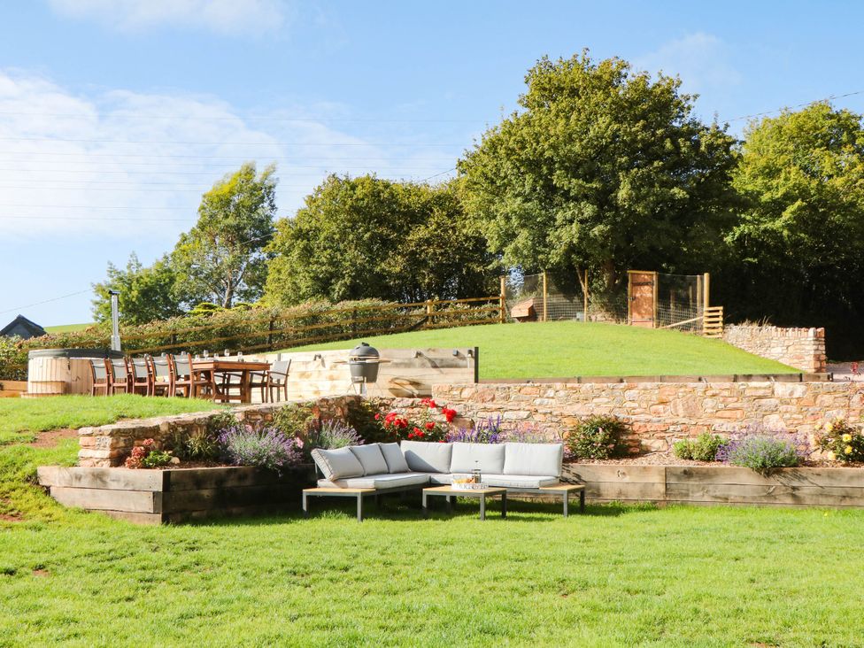 A garden with a sitting area and dining table at Higher Weekaborough Farm near Ipplepen