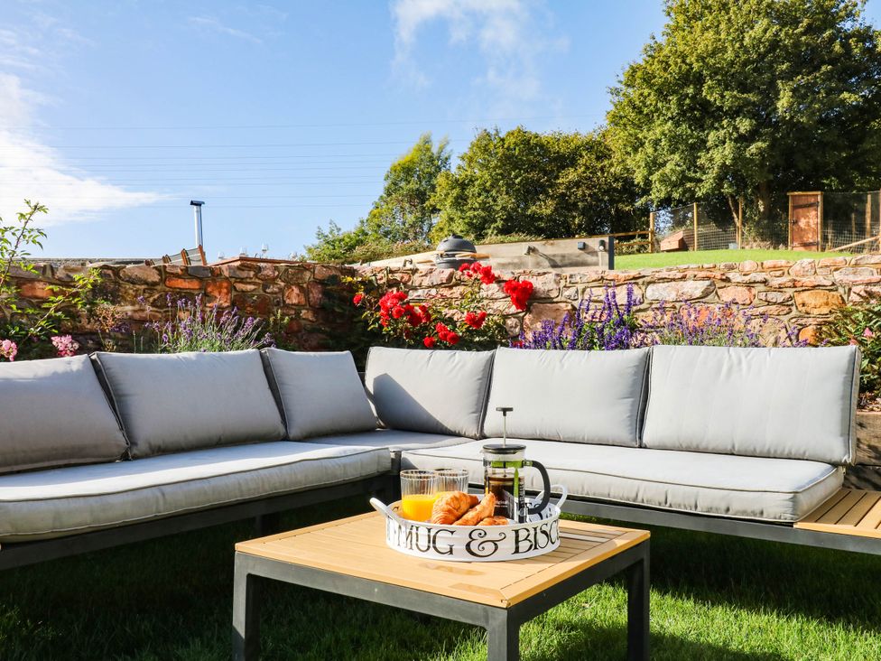 An outdoor seating area with sofa and table at Higher Weekaborough Farm in Coombe Fishacre near Ipplepen