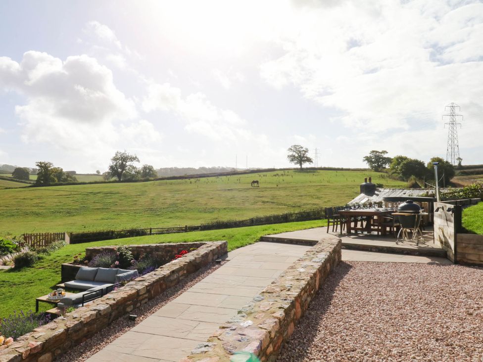 A garden with a couch and table overlooking the landscape at Higher Weekaborough Farm near Ipplepen