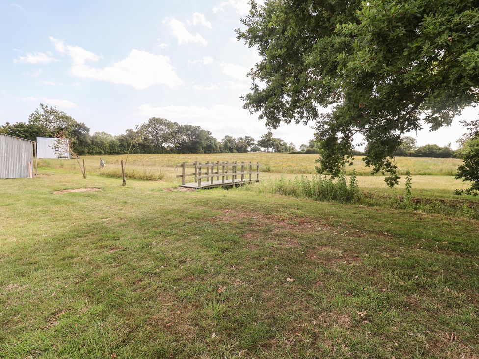 A garden with a wooden bridge and shed at Robin A-frame Monewden near Otley Suffolk