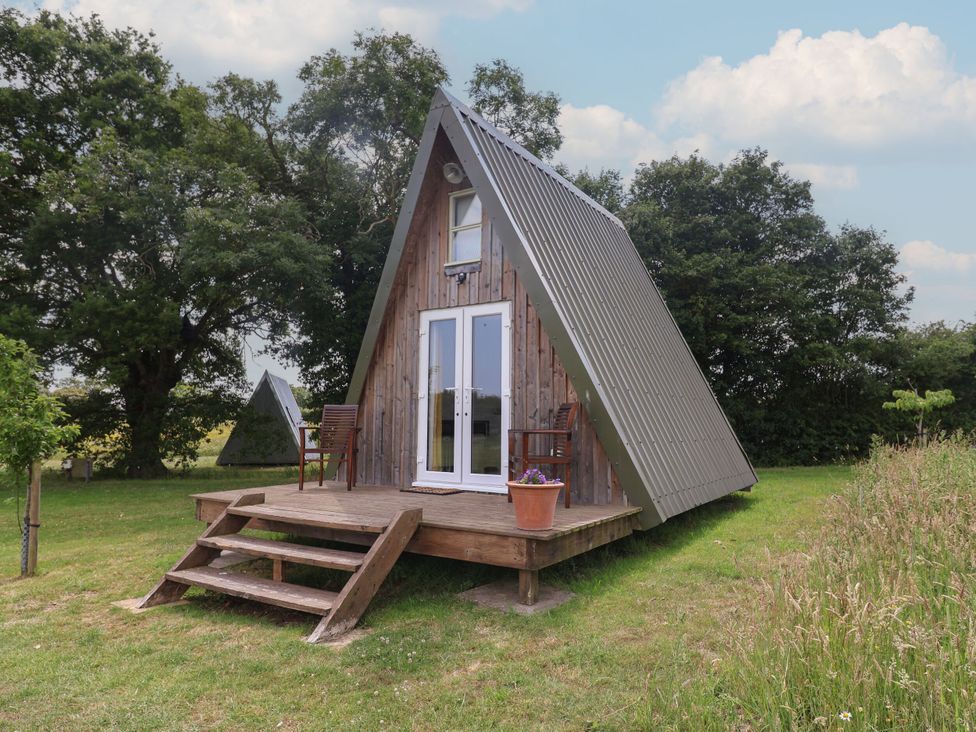 An A-frame house with a wooden deck and chairs at A-frame in Monewden near Otley, Suffolk