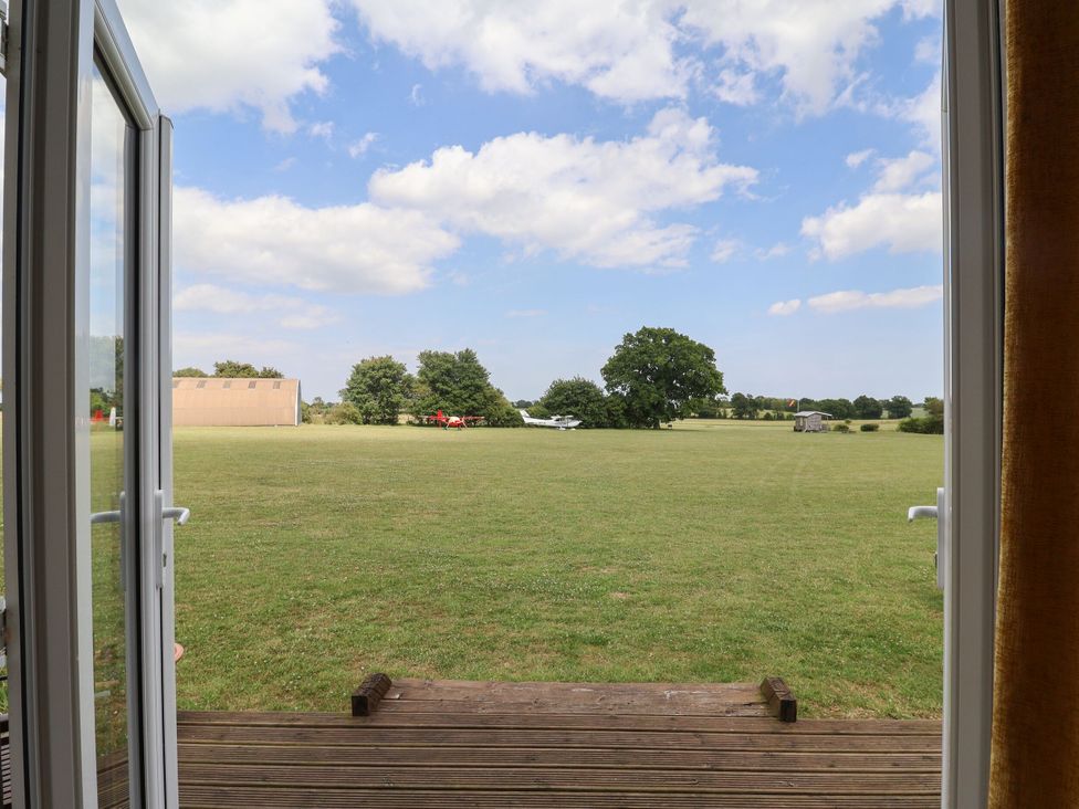 A view of a field with trees and an airplane from a cabin at A-frame in Monewden near Otley, Suffolk