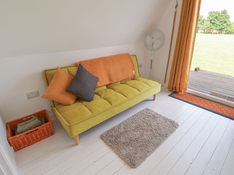 A snug with a green sofa and pillows at A-frame in Monewden near Otley, Suffolk