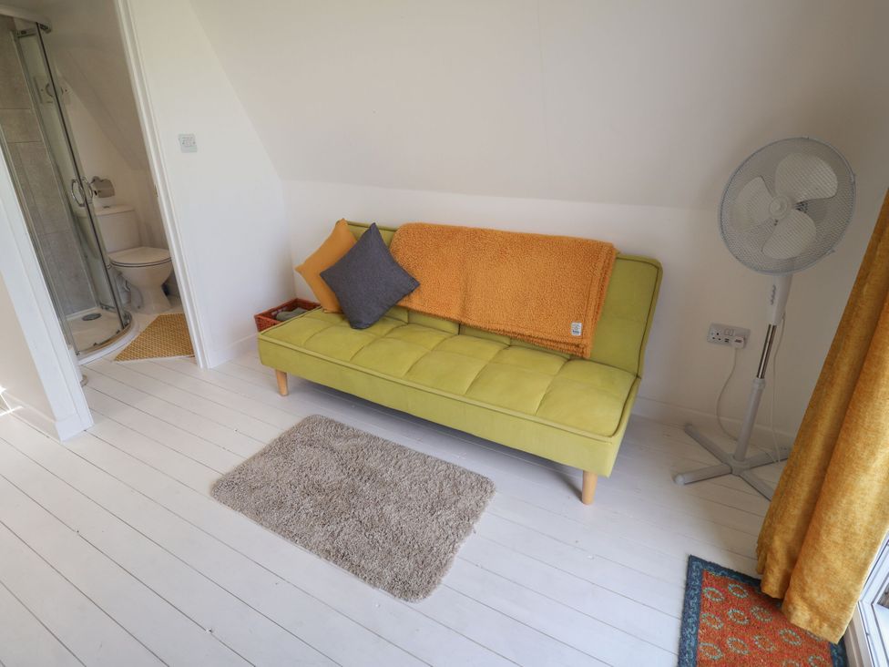 A room with a couch and fan near a bathroom at A-frame in Monewden near Otley, Suffolk