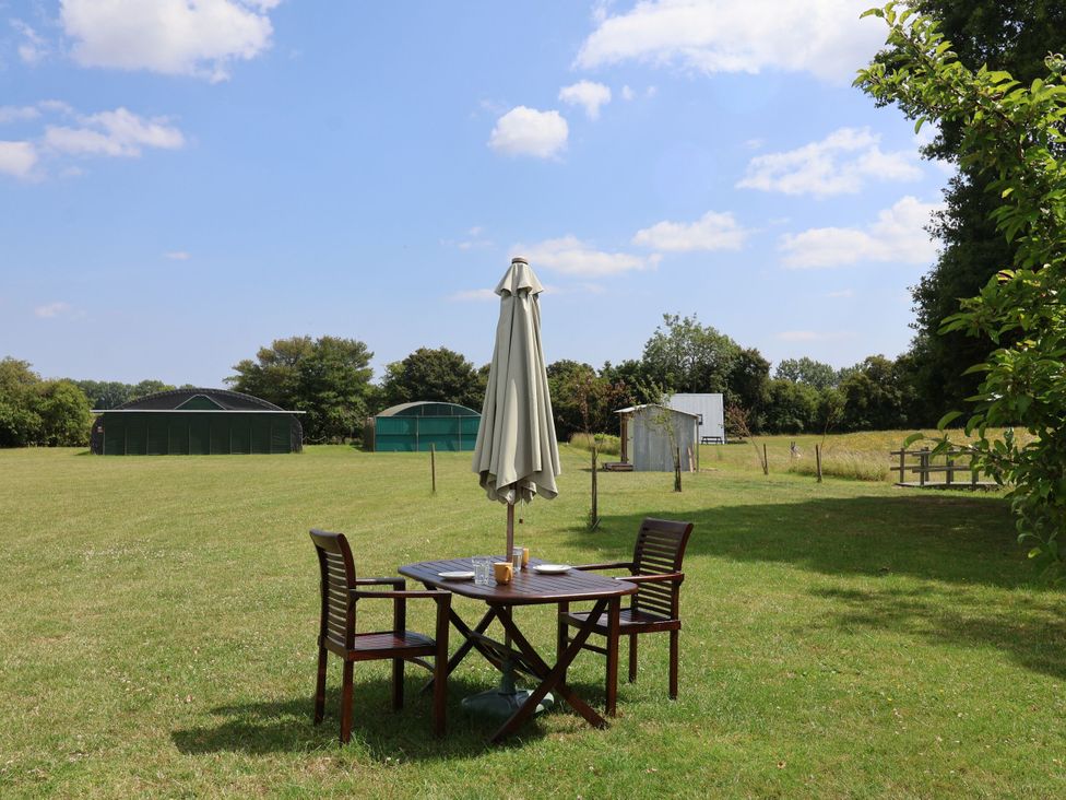 A table with chairs under an umbrella in an outdoor space at A-frame in Monewden near Otley, Suffolk