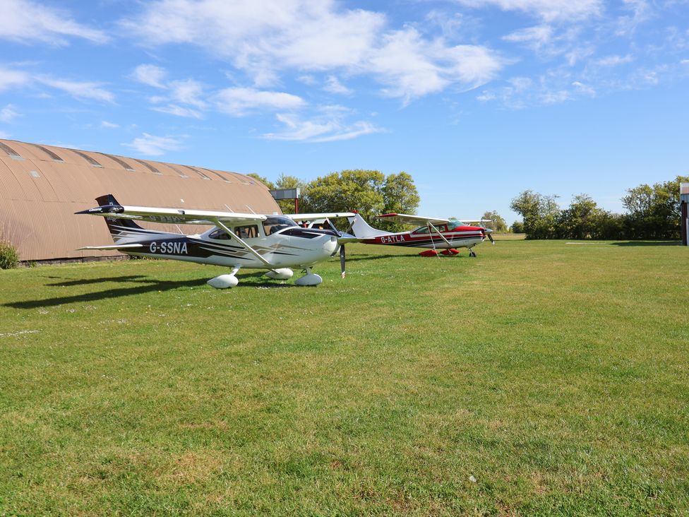 Two airplanes parked on grass near a hangar at A-frame in Monewden near Otley, Suffolk