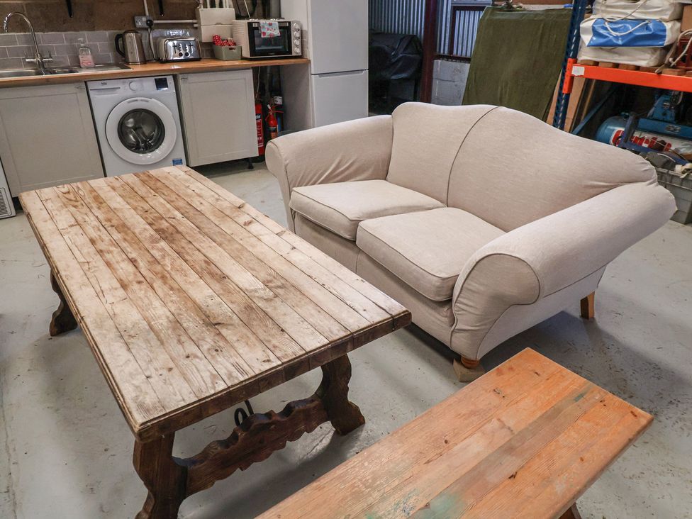 A sofa and coffee table in a room with kitchen appliances at A-frame in Monewden near Otley, Suffolk