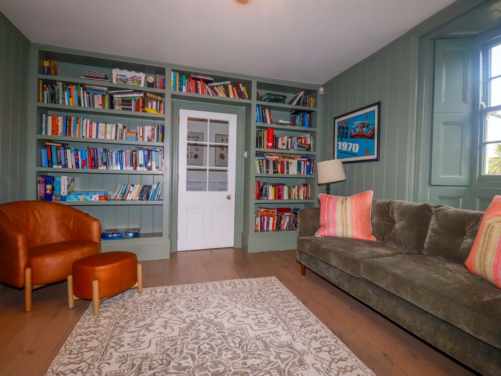 A living room with a bookshelf and a sofa at Vosporth Villa in Newquay