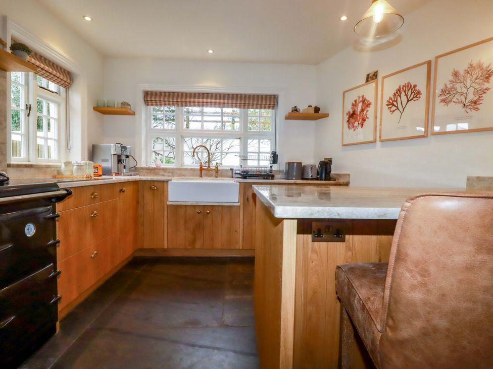 A kitchen with a sink and bar stool at Vosporth Villa in Newquay