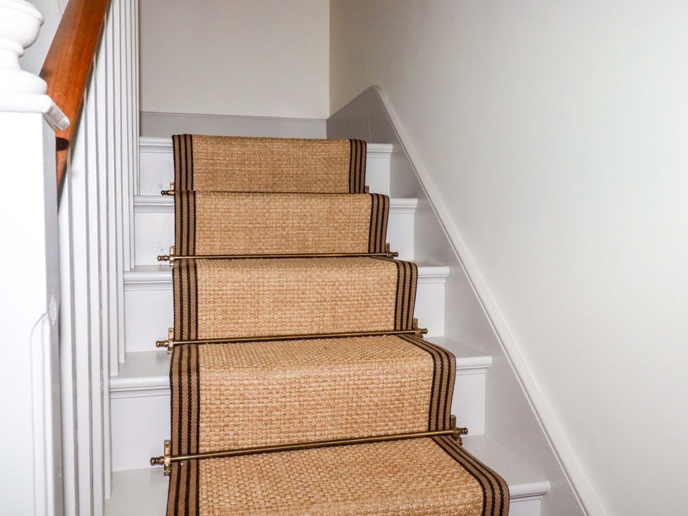 A staircase with a carpet runner and handrail at Vosporth Villa in Newquay