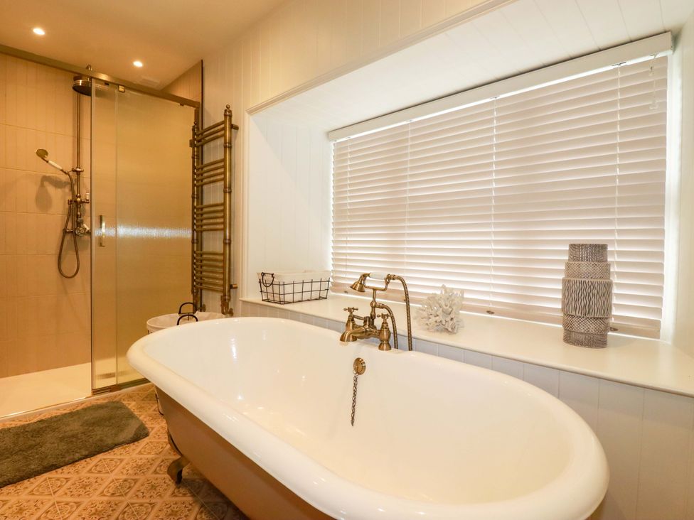 A bathroom with a bathtub and shower at Vosporth Villa in Newquay