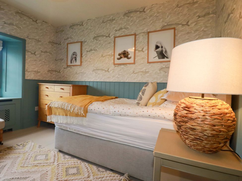 A bedroom with a bed and lamp at Vosporth Villa in Newquay
