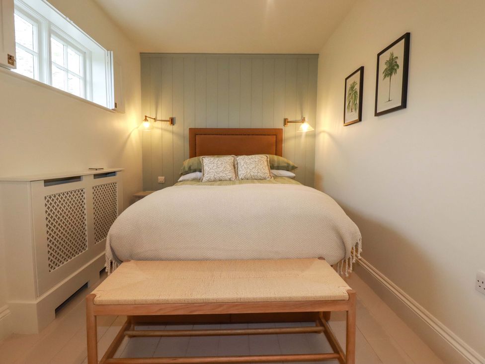 A bedroom with a bed and bench at Vosporth Villa in Newquay