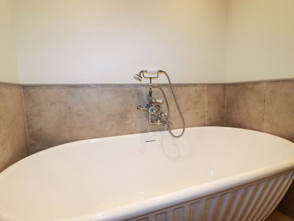 A bathroom with a bath tub and faucet at Vosporth Villa in Newquay
