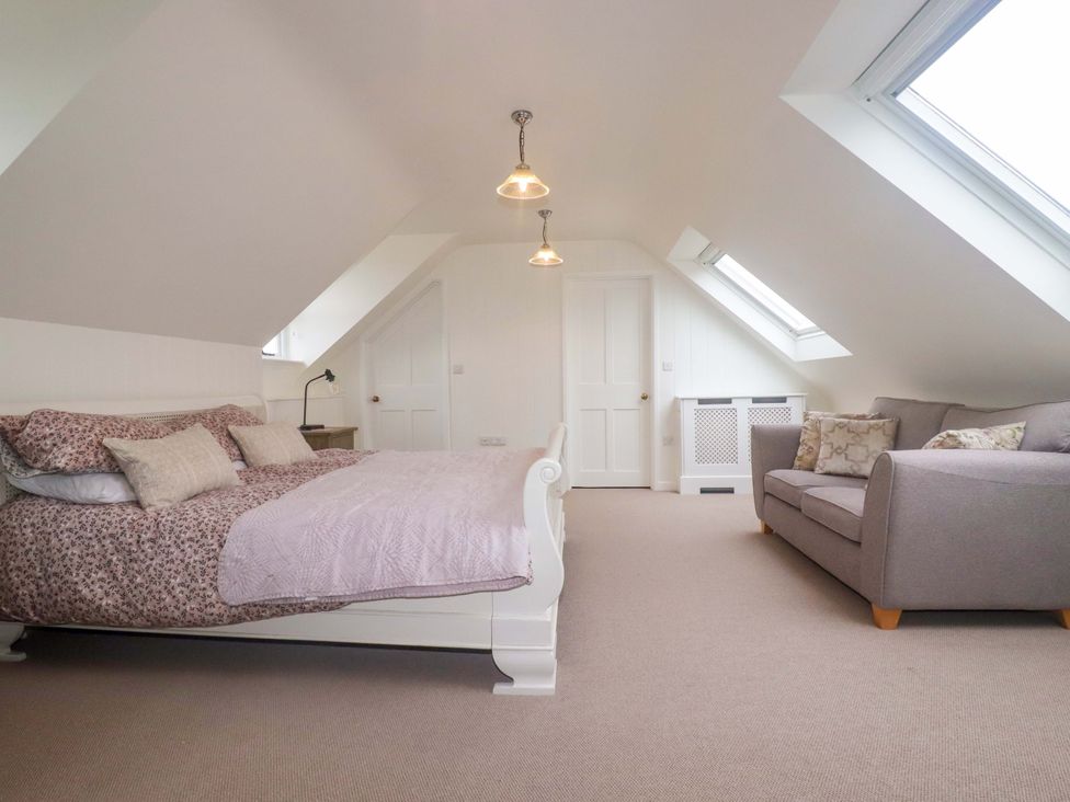 A bedroom with a bed and sofa at Vosporth Villa in Newquay