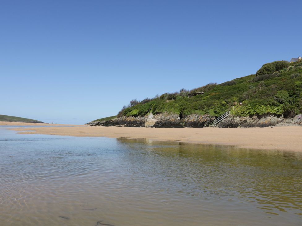 A beach with sand and water near a cliff at Vosporth Villa in Newquay