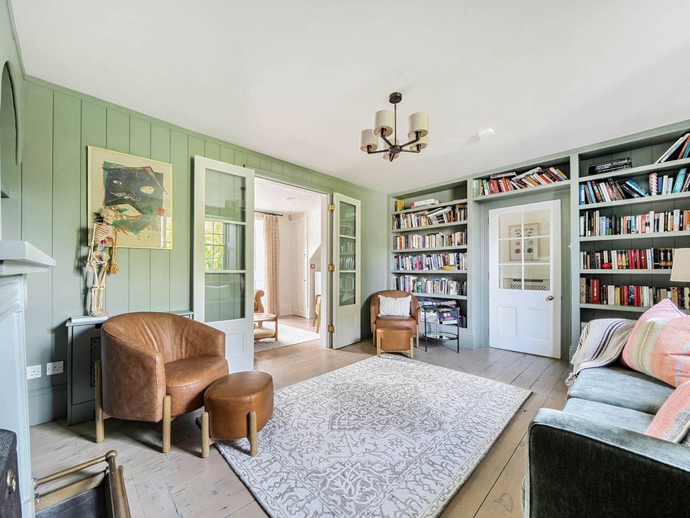 A living room with bookshelves and armchairs at Vosporth Villa in Crantock