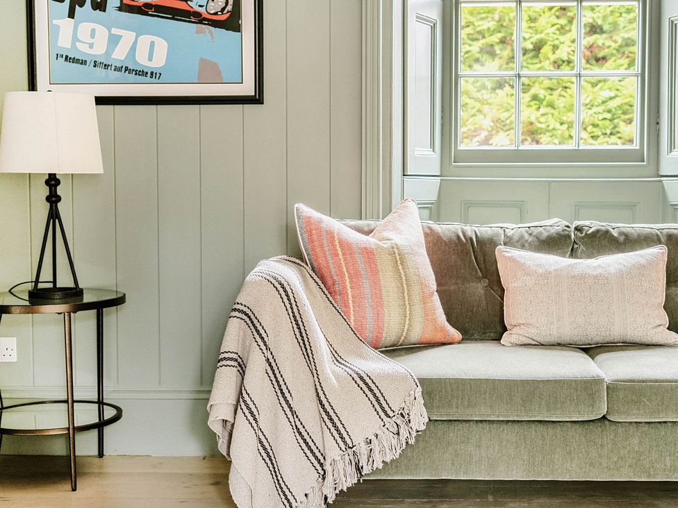 A living room with a couch and lamp at Vosporth Villa in Crantock