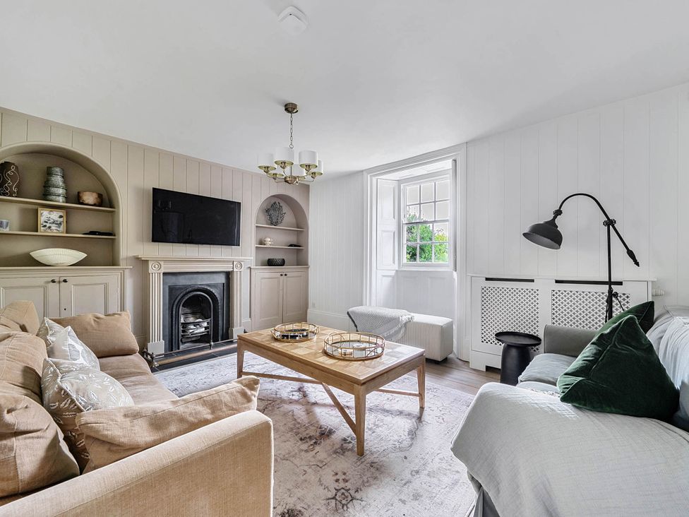 A living room with a fireplace and shelves at Vosporth Villa in Crantock