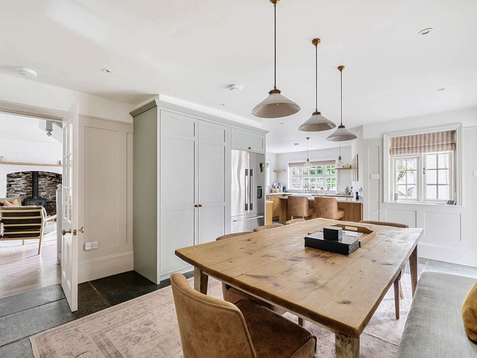 A kitchen with a dining table and bar stools at Vosporth Villa in Crantock