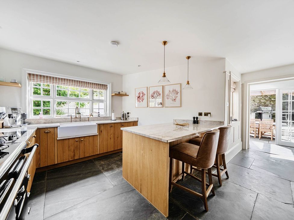 A kitchen with an island and bar stools at Vosporth Villa in Crantock