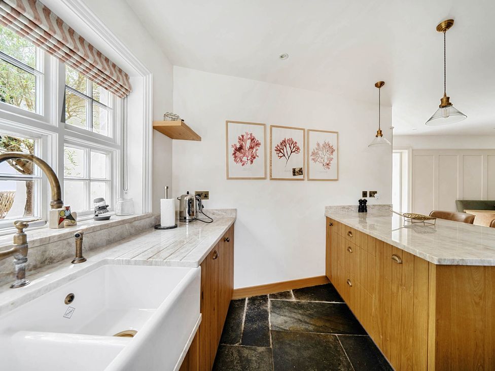 A kitchen with a sink and wooden cabinets at Vosporth Villa in Crantock