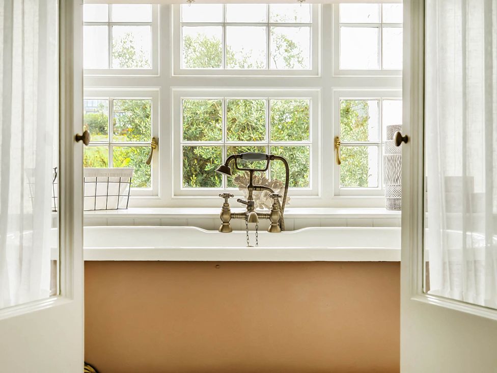 A sink with a faucet and windows at Vosporth Villa in Crantock