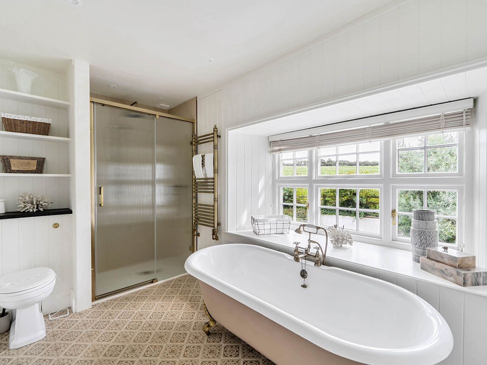 A bathroom featuring a bath tub, shower, and sink at Vosporth Villa Crantock