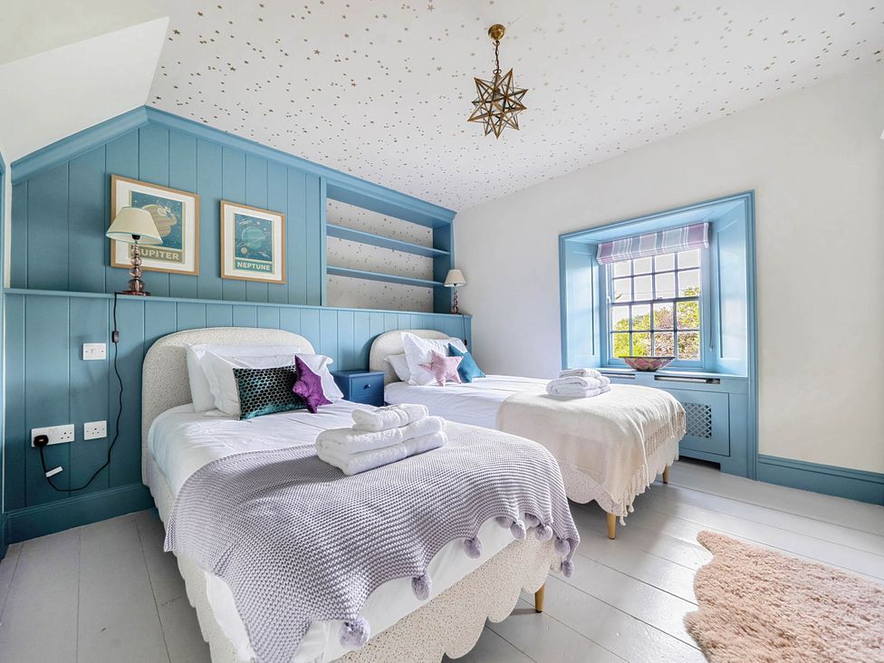 A bedroom with two beds and a window at Vosporth Villa in Crantock