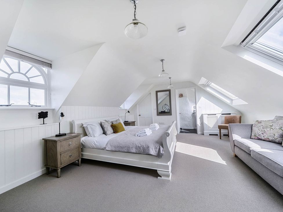 A bedroom with a bed and sofa at Vosporth Villa in Crantock